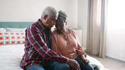 Senior man comforting depressed woman sitting in bedroom at home - shot in slow motion Stock Footage