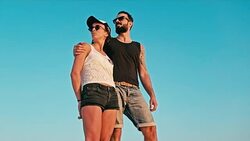 young woman and man enjoying the sunset in front of a blue sky Stock Footage