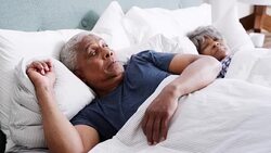 Worried senior man wakes up next to wife in bedroom - shot in slow motion Stock Footage