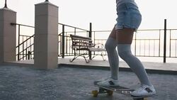 Young stylish attractive woman skateboarding at sunrise on seafront, slow motion Stock Footage
