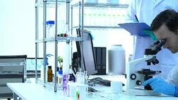Scientist is looking through microscope with colleagues working in modern laboratory or medical center together. Concept of science, testing development and lab industry. Stock Footage