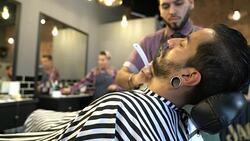 Young hairdresser shaving man with straight razor Stock Footage