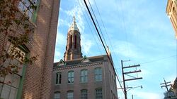 UP ANGLE OF THREE STORY BRICK CHURCH OR CATHOLIC SCHOOL WITH A CROSS ON TOP OF TOWER AND CUPOLA. Stock Footage
