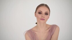 Happy fashion model posing indoors copy space handheld shot white background slow motion. Positive stylish woman stroking hair face wearing designer clothes dress. Make-up female cosmetics industry Stock Footage