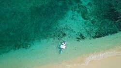 Drone shot aerial view of tropical Island and boat in turquoise pristine water. Directly above view Stock Footage