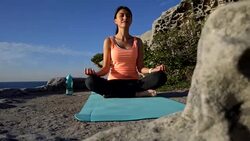 Young female adult meditating next to the sea looking peaceful Stock Footage
