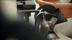 A cone-shaped tool used in glassblowing is returned to the rail where it is stored. Stock Footage