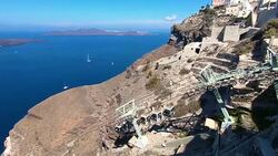 Gondola going up mountain in Fira, Thira overlooking the Caldera volcanic Aegean Sea with greek Orthodox cross in Santorini Greece Stock Footage