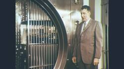 1960s: In bank, teller hands customer cash, customer counts Stock Footage