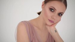 Elegant fragile girl with perfect make-up posing inside studio headshot slow motion rack focus. Stylish female model stroking hair looking at camera. Fashion industry beauty cosmetics products Stock Footage