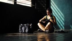 Panning young beautiful woman sitting on floor and wrapping hands with black boxing wraps in club. Stock Footage