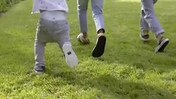 Three kids running on grass in slow motion Stock Footage