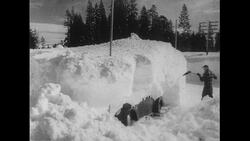 California, 1952: People shovel through almost 10 feet of snow as a postal worker skis to his a post office Stock Footage