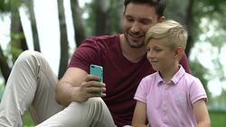 Male and child taking selfies, mugging for camera, family leisure with gadgets Stock Footage