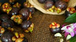 Top view of fresh delicious harvested mangosteens on wooden table. Thai organic purple fruit in the basket. Exotic natural blurred background with tropical flower. Healthy food and eating concept. Stock Footage