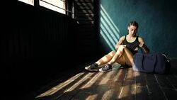 Panning young beautiful woman sitting on floor and wrapping hands with black boxing wraps in club. Stock Footage