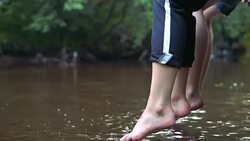 Teens relaxes by the river sitting on the edge of a wooden jetty. Stock Footage
