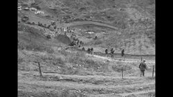 During Korean War, US soldiers in South Korea walking along path up hillside News Clip