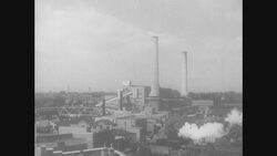 1950s: Train moves past large industrial complex Stock Footage