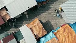 aerial drone footage of the morning city market with colorful tents looking down Stock Footage