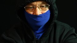 Man in hood and mask  typing laptop Stock Footage