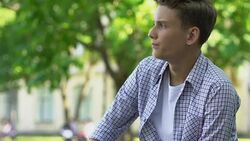 Teenage couple sitting apart on bench in park, first difficulties in relations Stock Footage