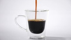 Pouring coffee into glass cup on white background Stock Footage