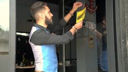Barber hanging open sign in Spanish on door Stock Footage