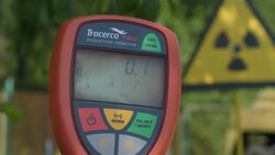 Handheld geiger counter and radiation warning sign News Clip