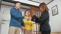 Realtor explain asian couple about house and give key to husband at new home and embracing each other.buying new house real estate Stock Footage