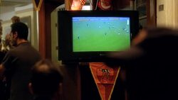 PULL BACK FROM CLOSE ANGLE OF TELEVISION SCREEN WITH SOCCER GAME PLAYING TO MEDIUM ANGLE OF SPORTS BAR. PATRONS VISIBLE. CHEERING. CELEBRATING. Stock Footage