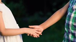 Boy tenderly taking little girl hand, shyly looking in her eyes, first love Stock Footage