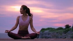 Happy young woman relaxing by practicing yoga on the beach at sunset, Sunrise background. Fitness, sport, yoga and healthy lifestyle concept. Stock Footage