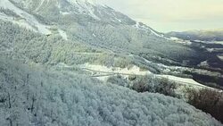 aerial of mountain valley on the winter snowy day through the clouds. Stock Footage