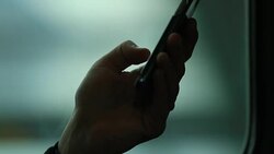 Close-up of person holding cellphone device while on a moving train. Blurred background moving in motion Stock Footage