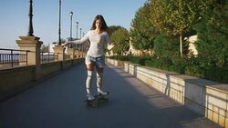 Young stylish attractive woman skateboarding at sunrise on seafront, slow motion Stock Footage
