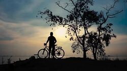 Silhouette of cyclist walking with bicycle at seaside, stretching exercise. Stock Footage