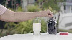 elderly hand dipping and stir a chocolate cookie In milk glass Stock Footage