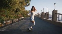 Young stylish attractive woman skateboarding at sunrise on seafront, slow motion Stock Footage