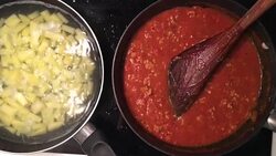 A chef in a professional kitchen cooking homemade tomato sauce and mashed potatoes in metal pan on rustic table background in the kitchen. Concept diet, food, Italian and nutrition. Stock Footage