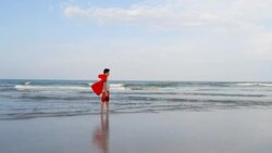 Asian preteen boy in red cover standing on the beach with superhero concept, slow motion. Stock Footage