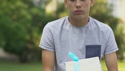 Teenage boy holding present, waiting for girlfriend, nervous about first date Stock Footage
