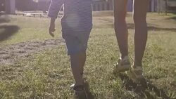 Parent walking with son in park with lens flare Stock Footage