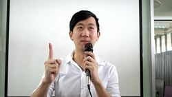 Portrait of young handsome Asian male speaker publicly speaking on stage to group of audience with white board behind Stock Footage
