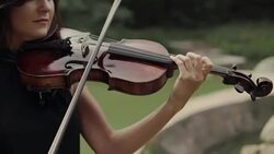 Young beautiful girl in black dress plays violin staying on bridge outdoors Stock Footage