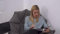 Beautiful girl thumbs a magazine in the chair Stock Footage