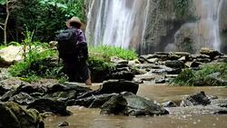 Adventurers Senior man. walking through small stream river of waterfall in the forest. Adventures and extreme tourism, overcoming obstacles. Travel Lifestyle and success concept. Video Slow motion Stock Footage