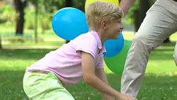 Loving parents congratulating little boy on birthday, outdoor party in park Stock Footage
