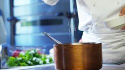 in an Italian professional kitchen a chef pours salt on a dish or in the water to boil the Italian pasta concept of healthy and light food. Stock Footage