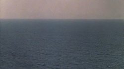 WIDE ANGLE OF OCEAN, AIRCRAFT CARRIER OR MILITARY, NAVY SHIP HIT WITH LASER BEAM AND SHRINKS THEN DISAPPEARS. SCIENCE FICTION. SPECIAL EFFECTS. Stock Footage